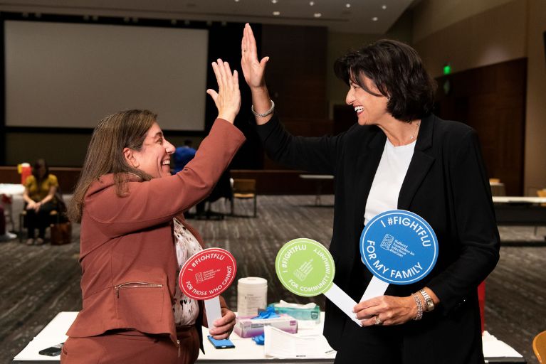 Rochelle Walensky and Debra Houry high five while holding #FightFlu paddles