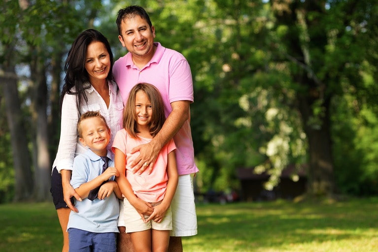 Family smiling holding each other on a grass field