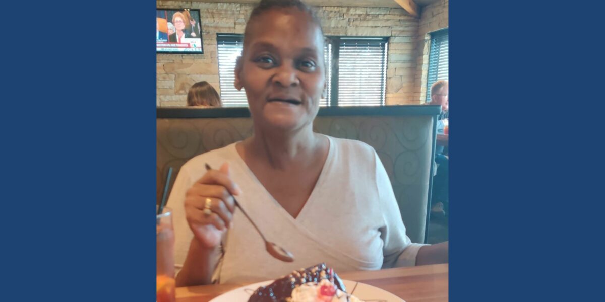 A woman sits in a restaurant booth eating cake