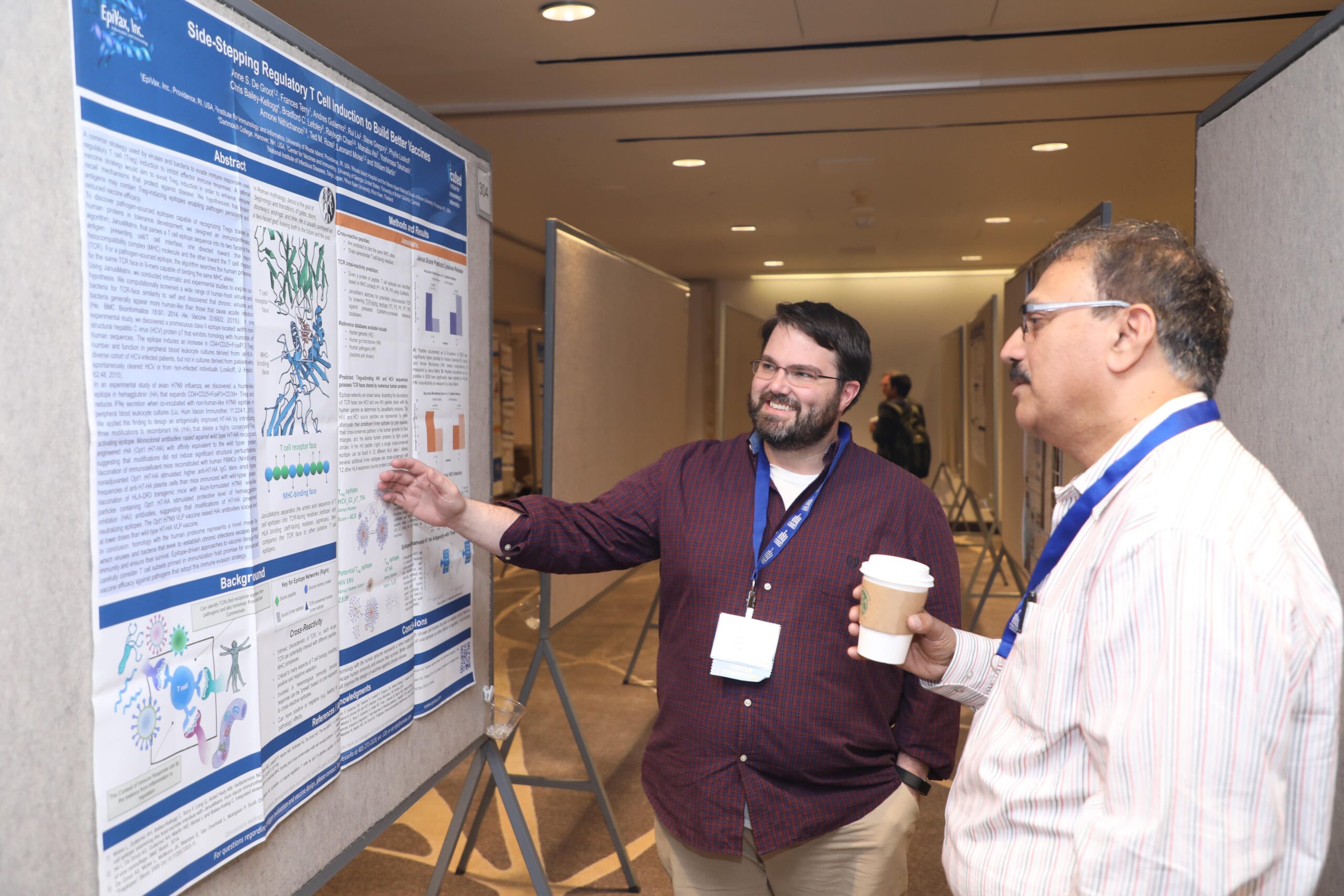 Two men stand in front of a poster.