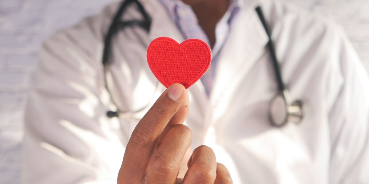 Profesional de la salud sosteniendo un corazón de papel rojo