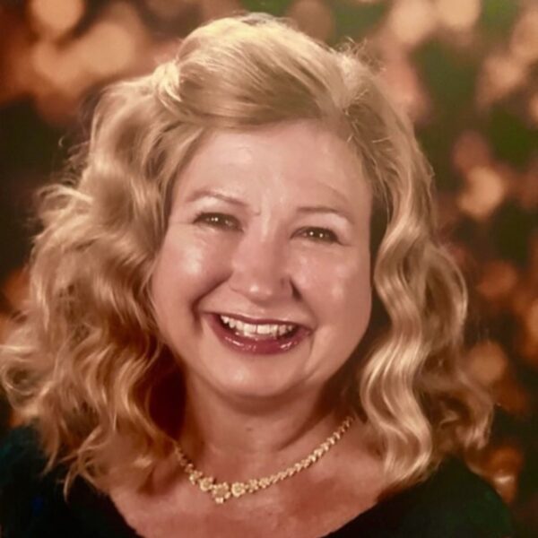 A woman with curly blond hair smiles