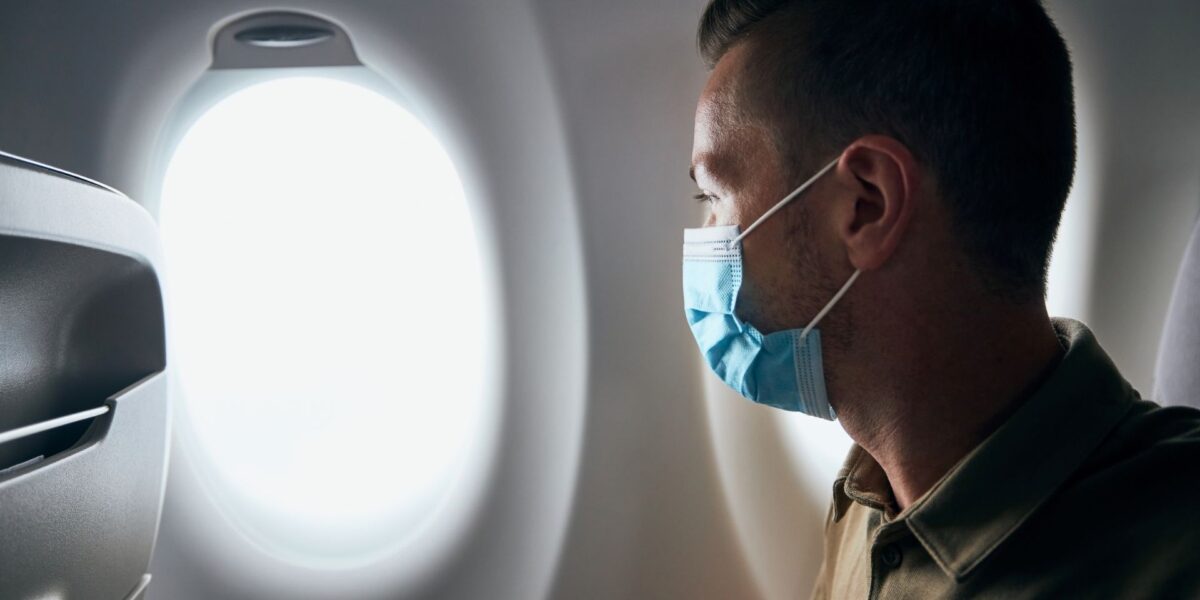 Un hombre con una mascarilla mira por la ventana de un avión durante un vuelo